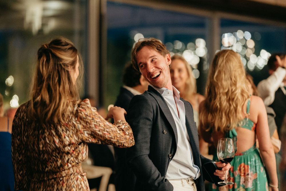 Wedding guests dance and celebrate during an evening reception under twinkling lights.