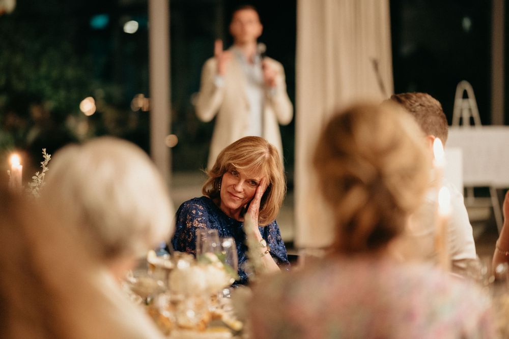 Dinner guests listen attentively during a speech at an elegant candlelit reception.