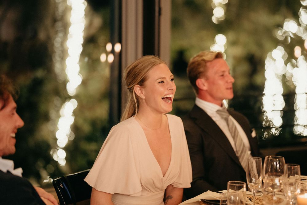 Wedding reception guests sharing joyful laughter during evening dinner celebration.