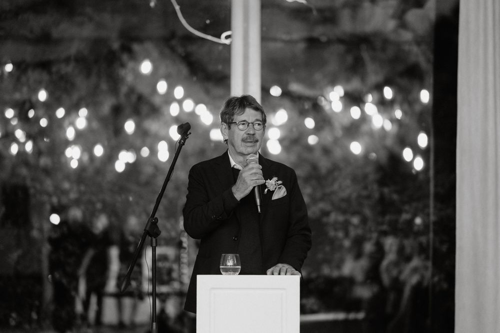 Speaker giving emotional wedding toast at candlelit reception podium.