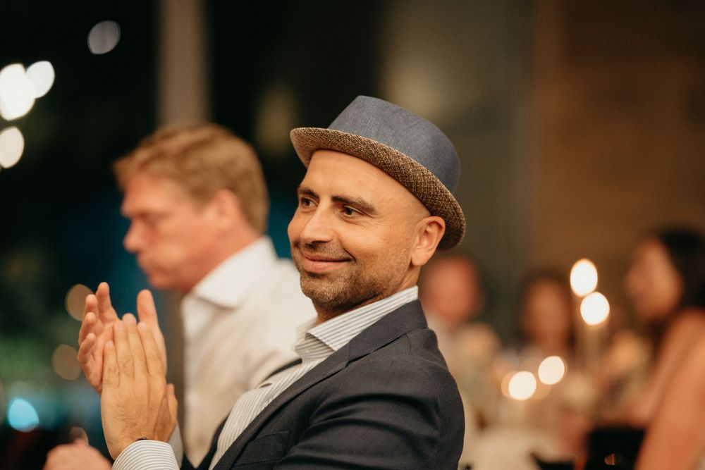 Guest in formal attire applauding during an evening wedding reception.