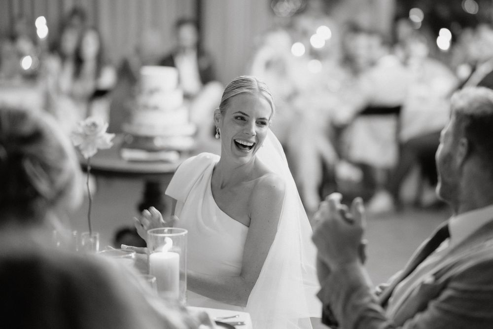 A candid black and white moment captures a joyful celebration at a wedding reception.