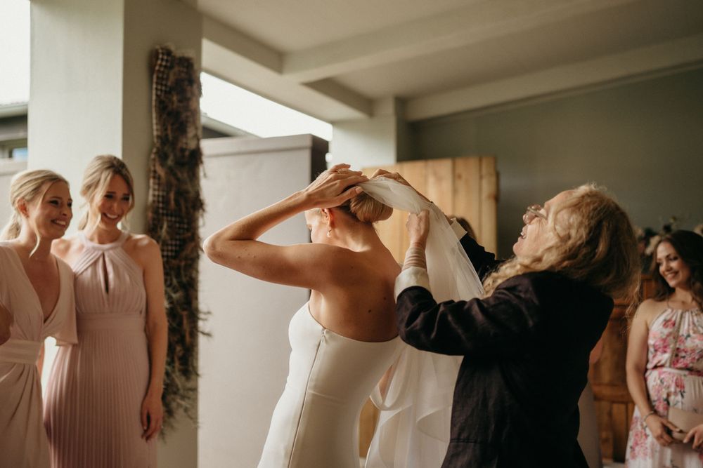 Wedding preparation scene with attendants helping with final touches indoors.