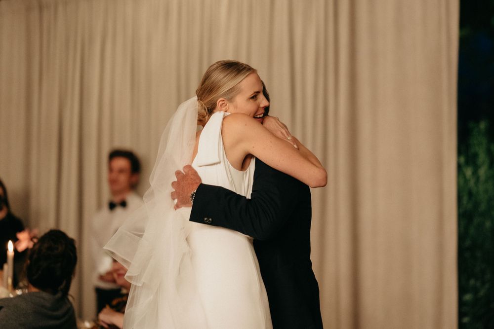A tender embrace between partners during an emotional first dance moment at an indoor wedding reception.