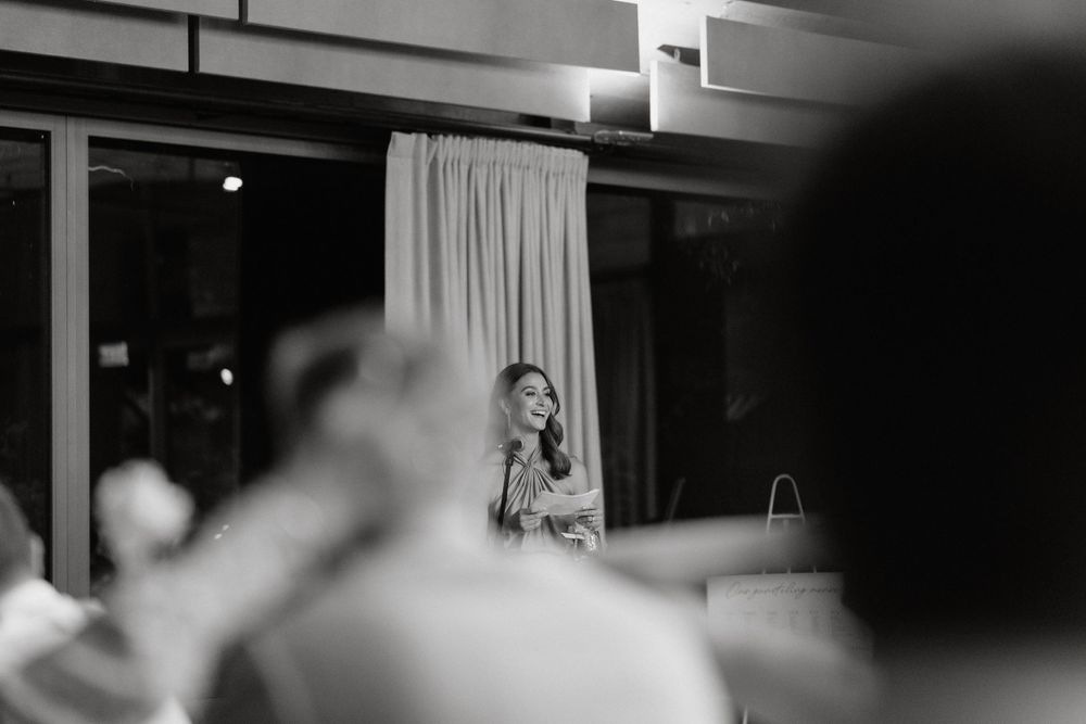 Black and white photograph of an evening wedding reception with soft lighting and curtains.