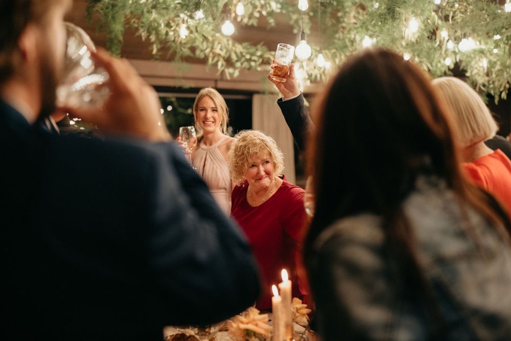 Wedding guests raise their glasses in a celebratory toast during an evening reception.