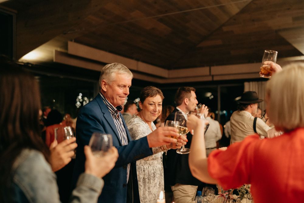 Wedding guests raise glasses in a celebratory toast during an indoor reception.