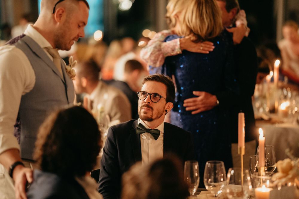 Guests enjoying conversation around a candlelit wedding reception table.