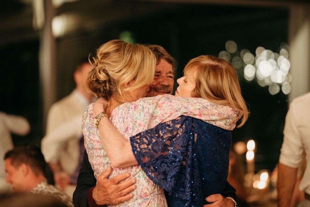 Emotional embrace between wedding guests during evening reception celebrations.