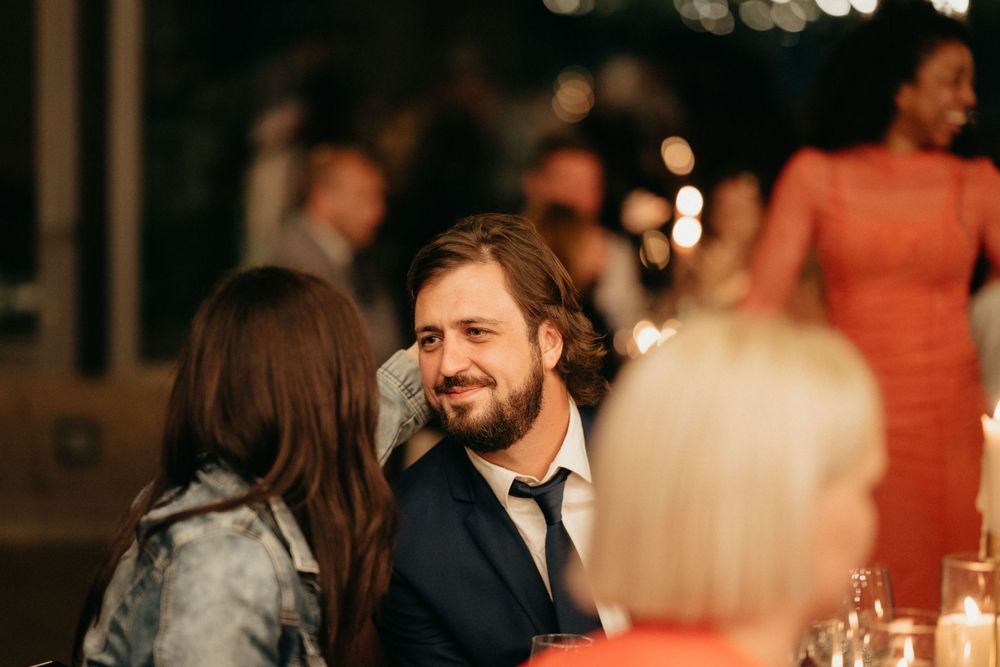 Wedding reception guests engaged in conversation at candlelit dinner table.