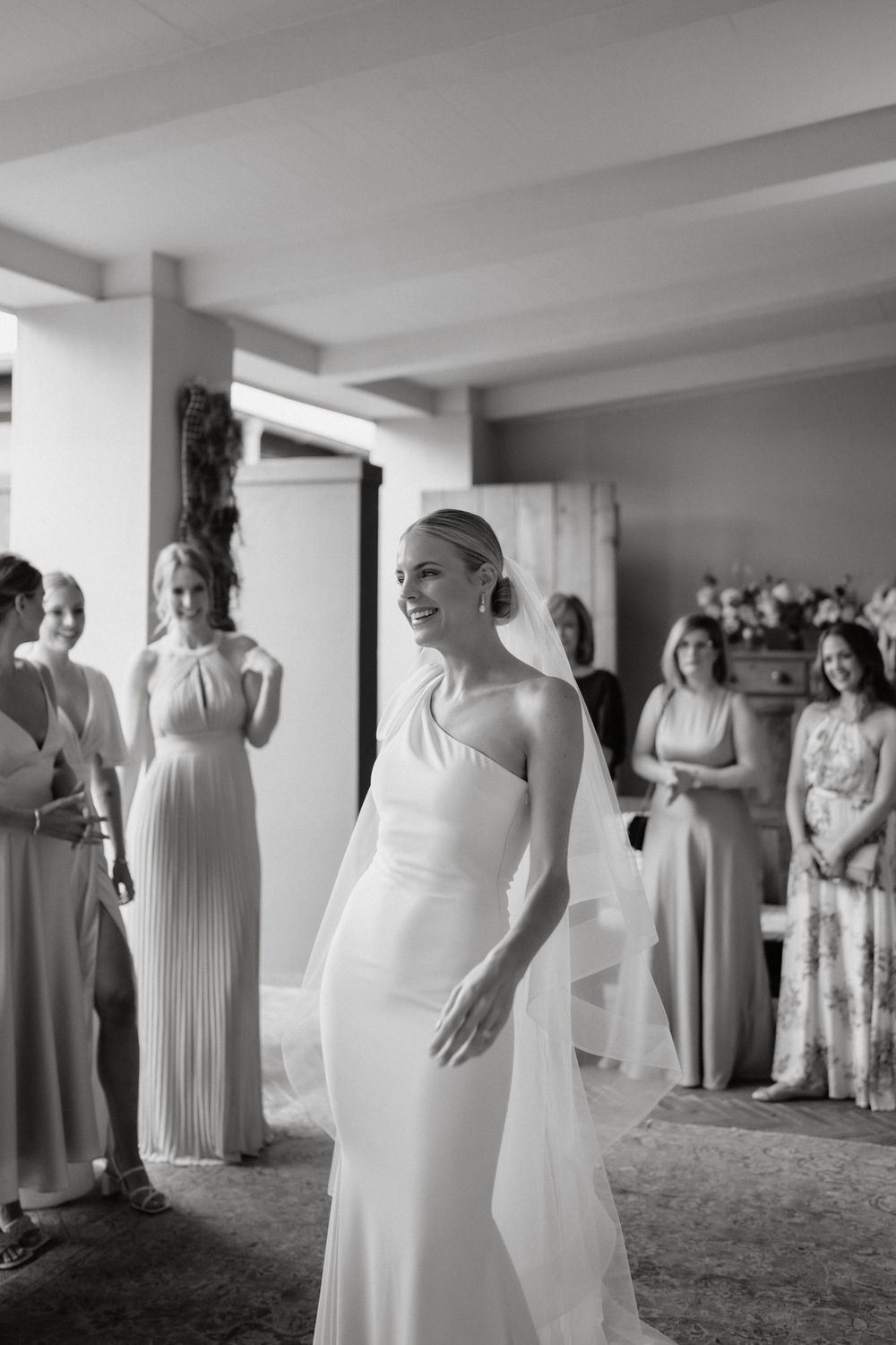 Elegant wedding scene with attendants in flowing gowns gathered in an indoor space.