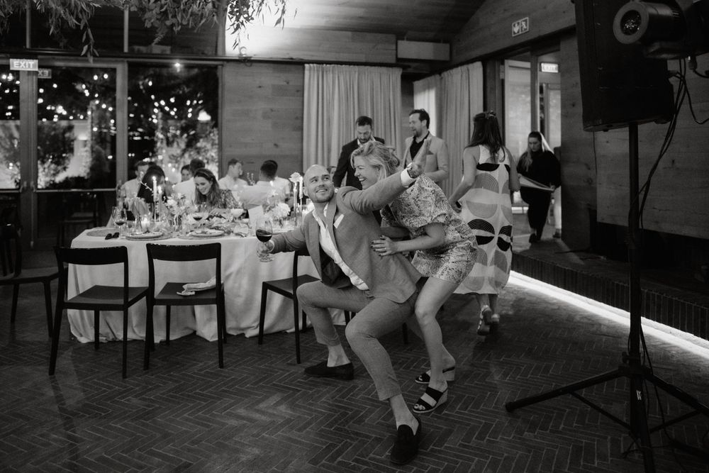 Black and white photo of guests dancing energetically at a wedding reception.