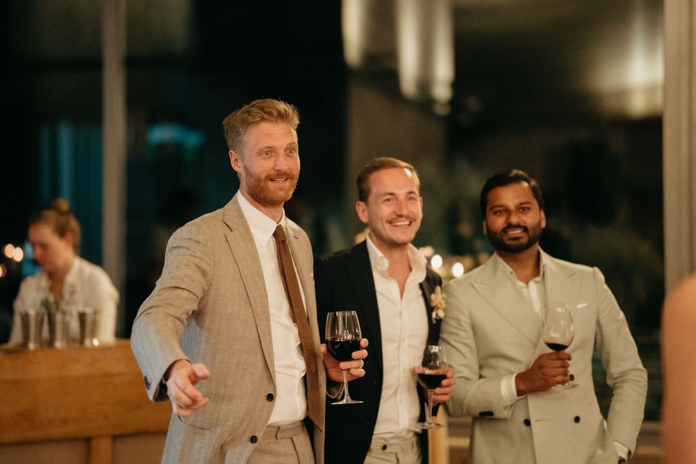 Three well-dressed friends share drinks and smiles at an evening celebration.