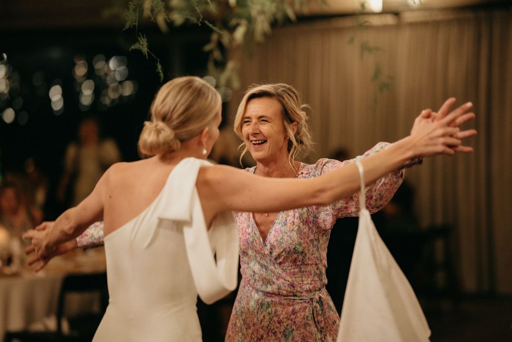 Two people dancing and embracing with joy during a wedding reception.