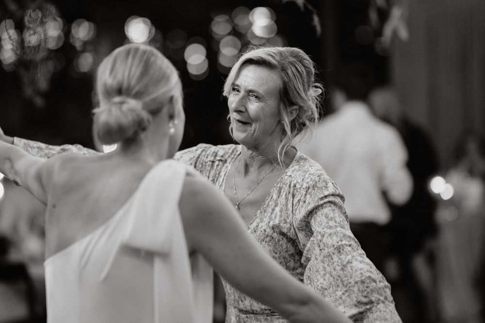 Two people dance together at a celebration in black and white photography.