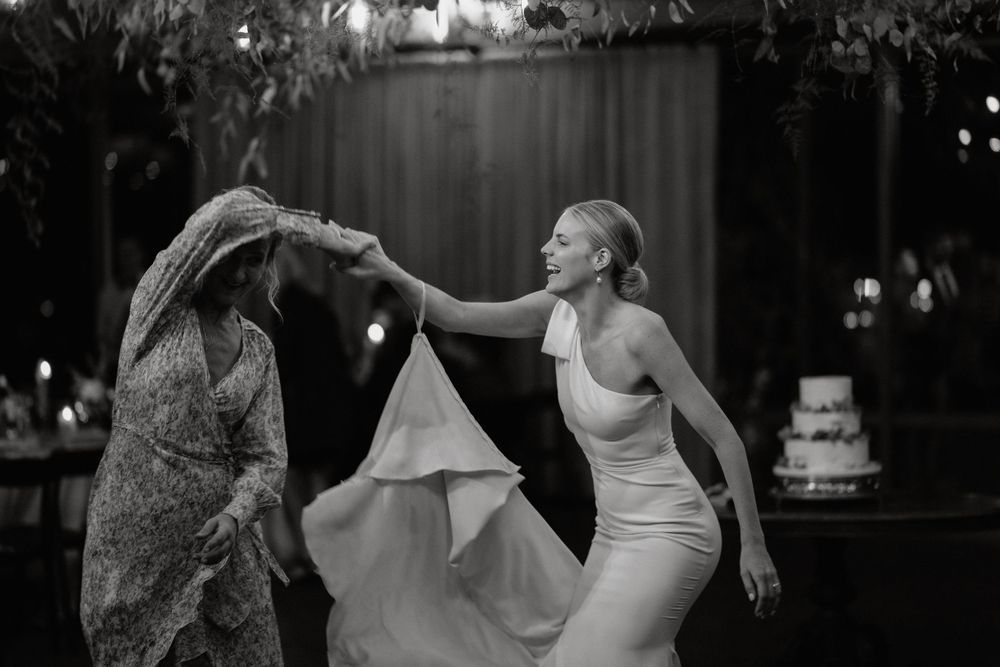 Black and white photo captures energetic dancing moment at wedding reception.