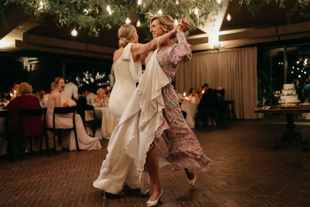 Dancers twirling on the dance floor at an evening wedding reception with dramatic lighting.