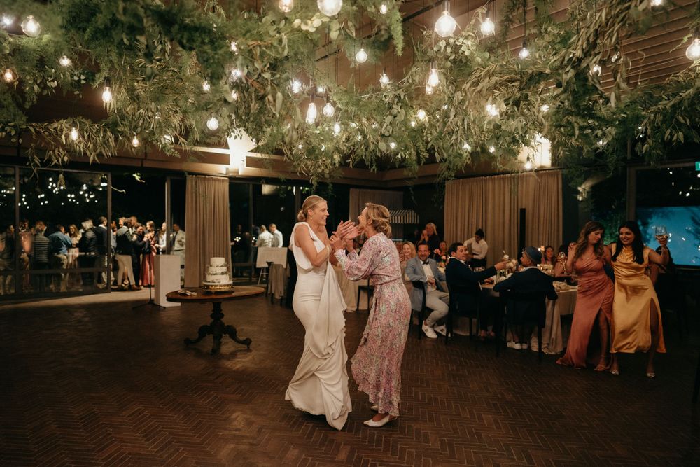 Romantic dance scene under twinkling lights and greenery at an elegant wedding reception.