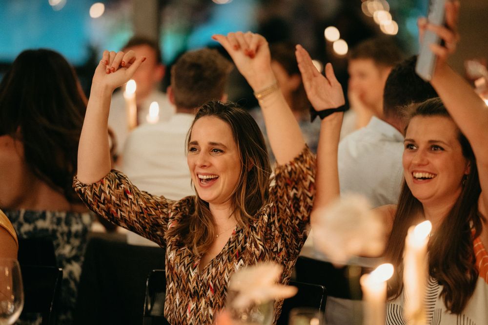 Guests dancing and celebrating joyfully at a lively evening party with soft bokeh lights in the background.