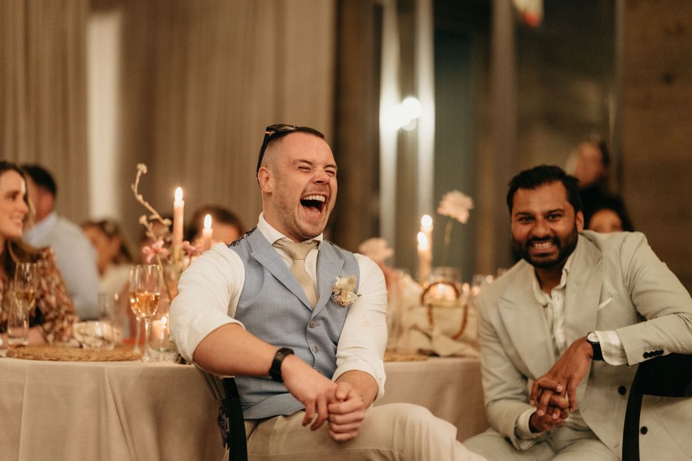 Wedding guests share joyful laughter during reception dinner.