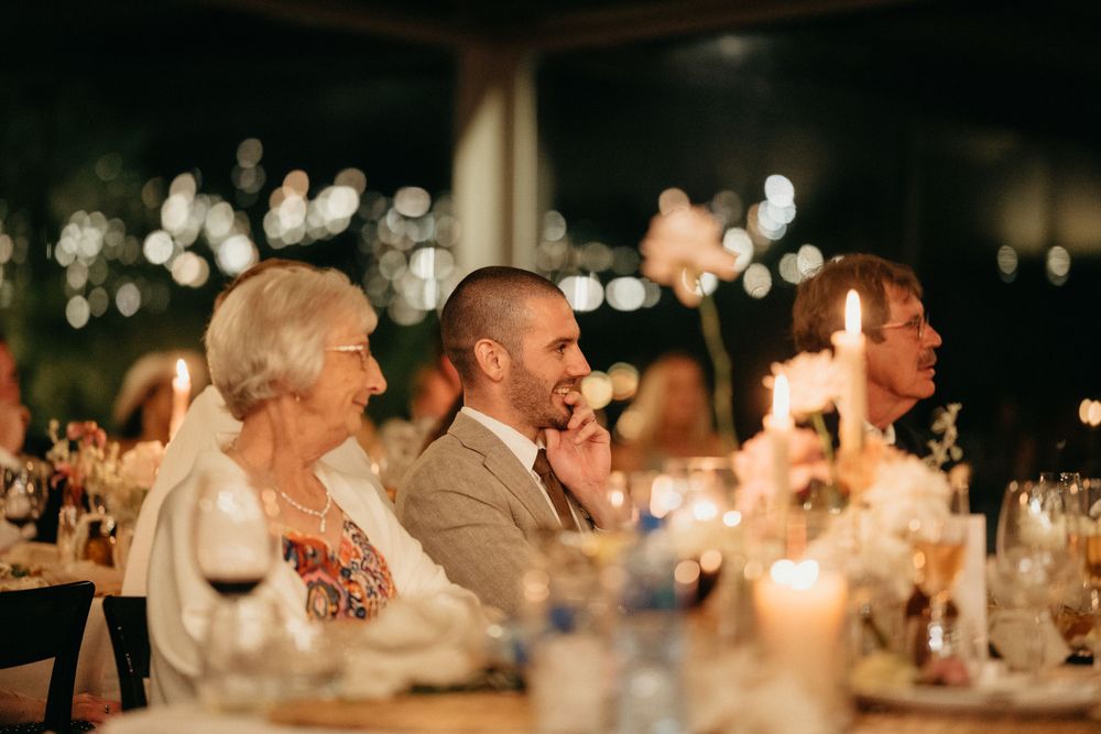 Guests enjoy a candlelit dinner at an evening wedding reception.