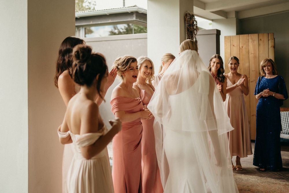 A group gathers in preparation for a wedding celebration in a sunlit interior space.