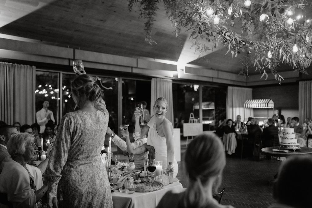Black and white photo of wedding guests celebrating during an indoor reception.
