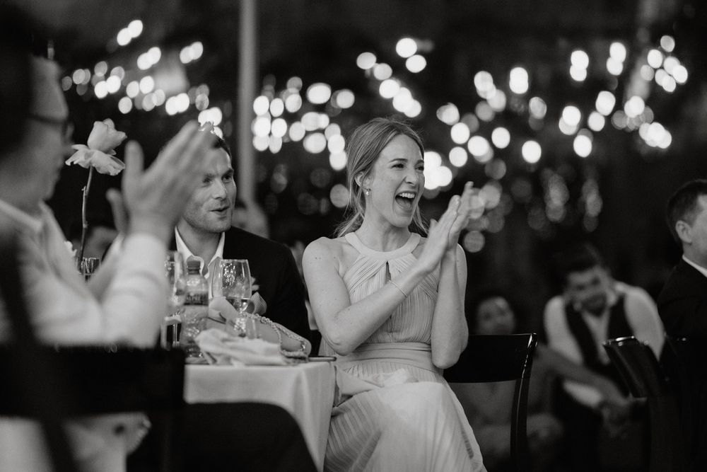 Black and white photo of wedding guests clapping and celebrating during the reception.