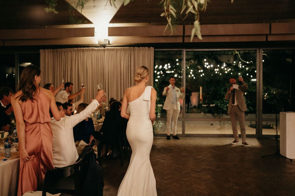 Bride in fitted wedding gown celebrating with guests during the reception.