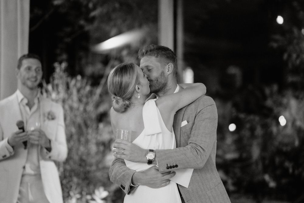 A happy couple embraces on their wedding dance floor during their first dance in black and white.