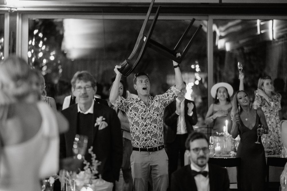 Wedding reception guests celebrate on the dance floor in black and white photography.