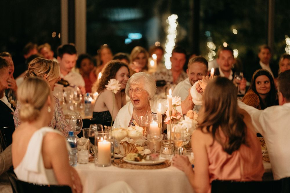 Wedding guests celebrate around a table with sparklers and candlelight during an evening reception.