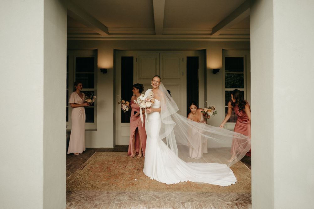 Wedding moment captured in a white corridor with flowing dress and veil movement.