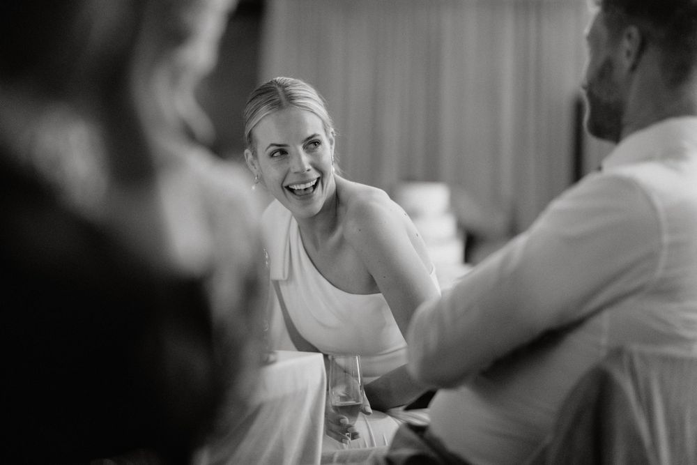 A black and white wedding photo shows laughter and joy during the reception festivities.