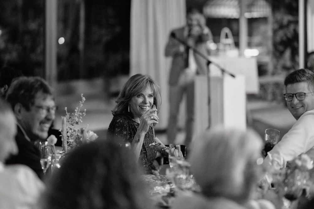 Black and white candid shot of guests during wedding reception dinner.