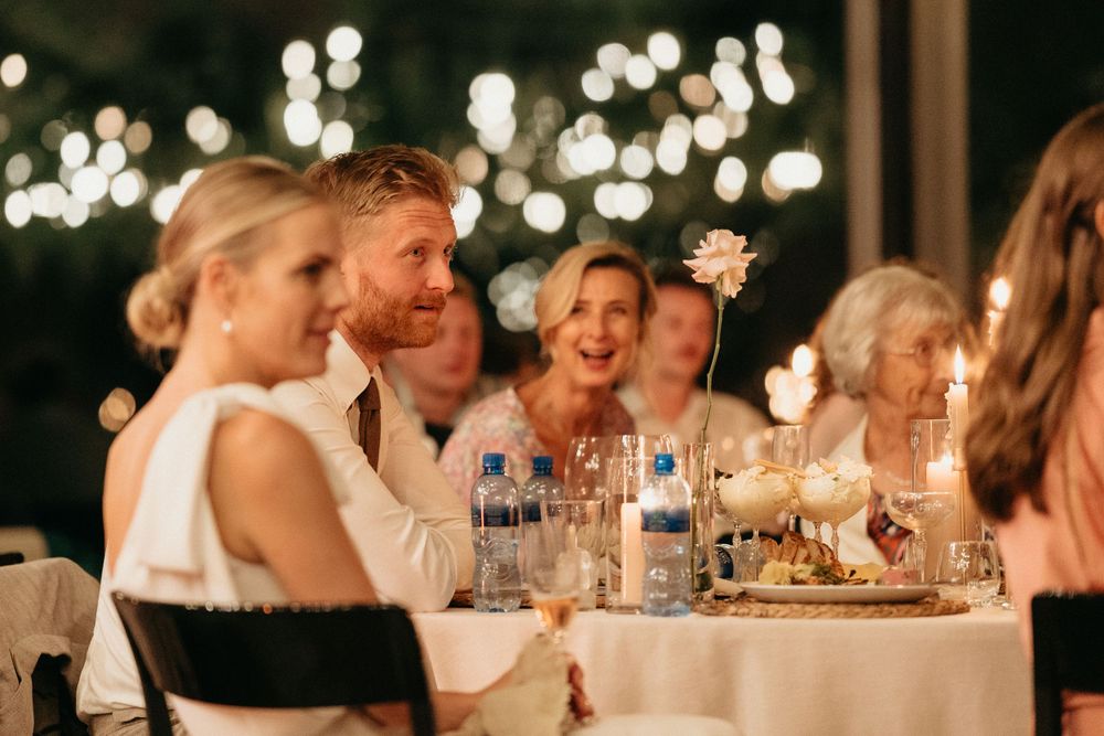 Wedding reception dinner scene with guests enjoying conversation under string lights.