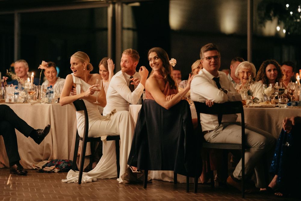 Wedding guests sitting at reception tables react emotionally to speeches or toasts.