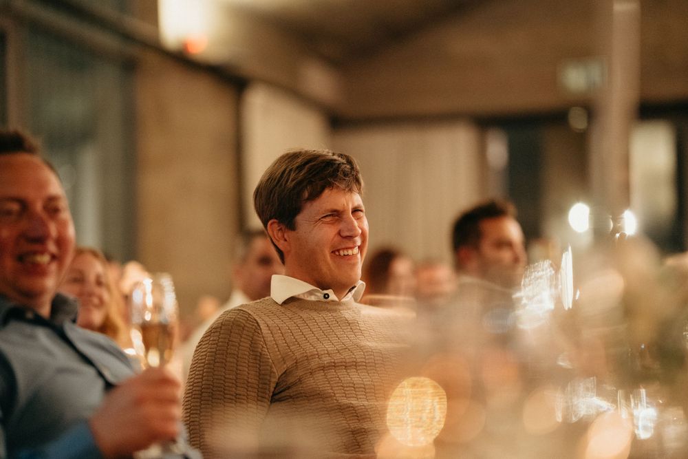 Wedding guests smile and laugh during an intimate candlelit reception celebration.