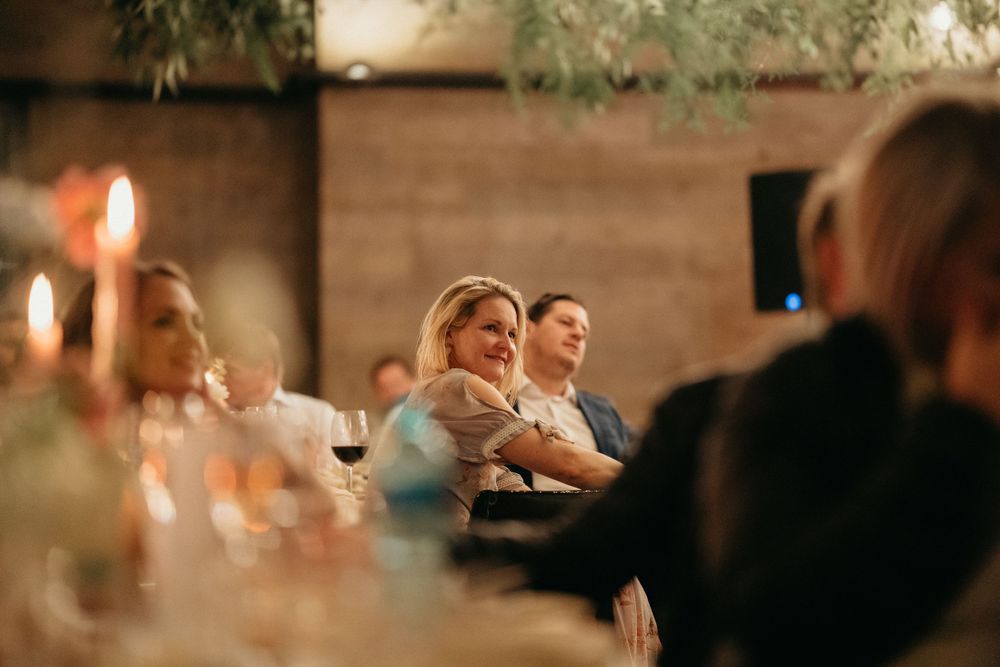 Candlelit reception dinner with guests seated at tables in warm atmospheric lighting.