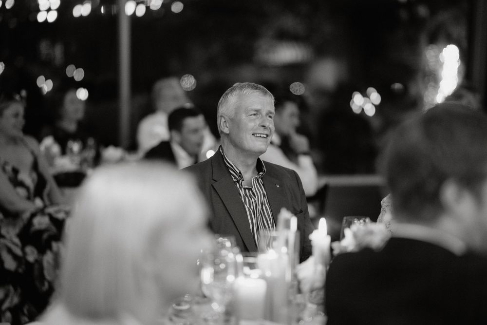 Black and white candid photo of guests enjoying themselves at an elegant dinner reception.