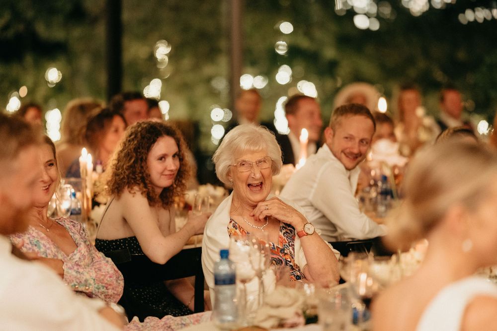 Wedding reception guests sharing laughter during evening dinner celebration.