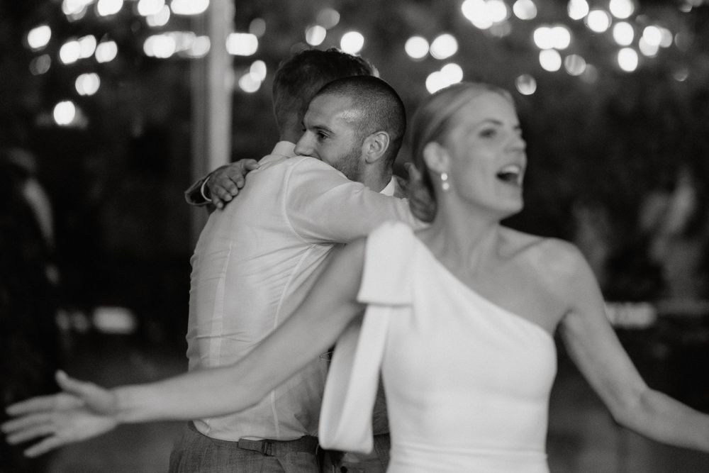 A joyful couple sharing their first dance at a wedding reception with twinkling lights in the background.