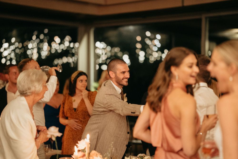 Wedding reception guests mingle and dance at a lively evening celebration.