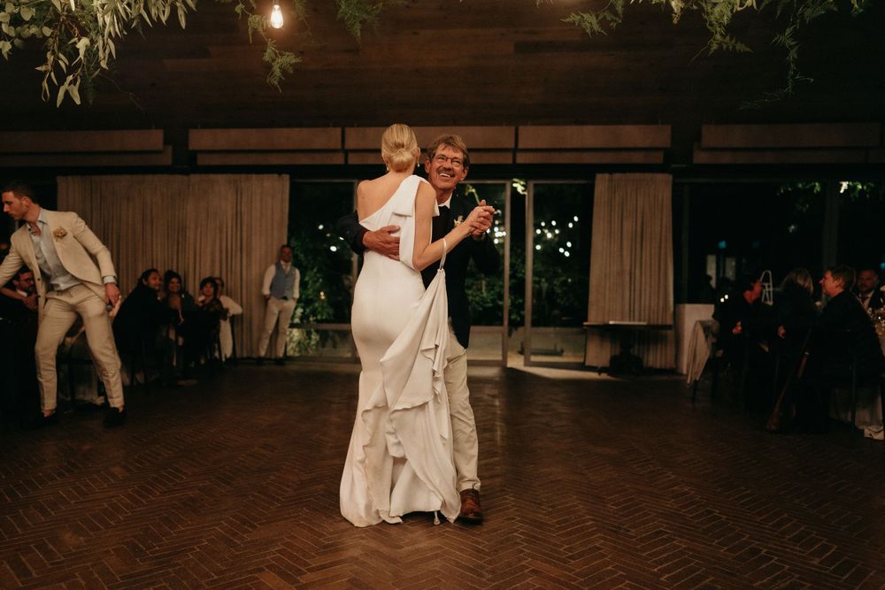 Couple sharing their first dance at wedding reception in dimly lit venue.