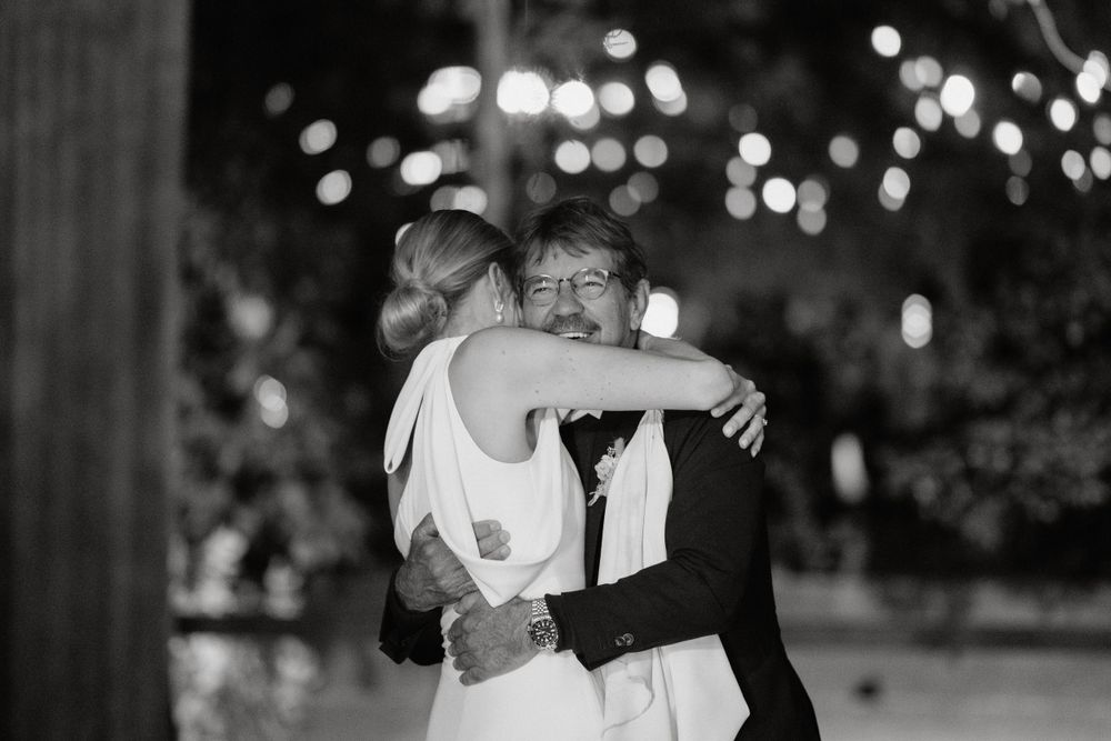 A couple shares an intimate dance moment under twinkling lights at their wedding reception.