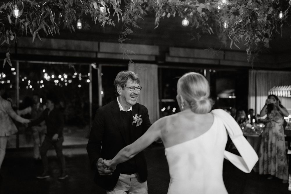 Dancing couple enjoying a moment on the dance floor at a wedding reception under twinkle lights.