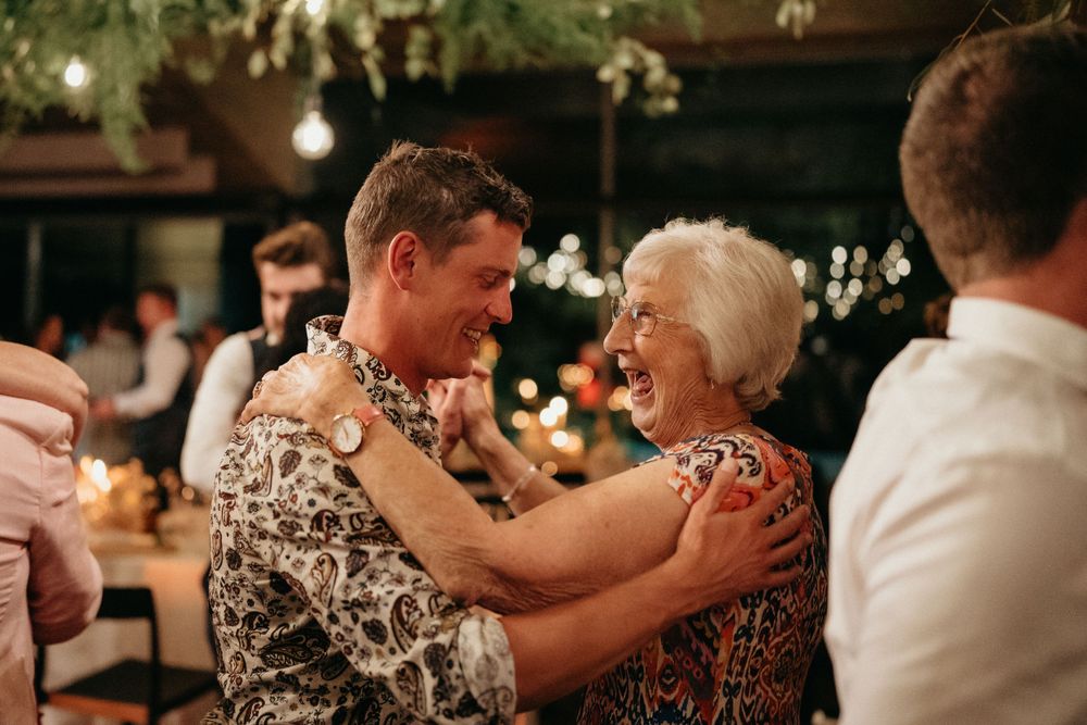 Two people share an emotional dance moment under warm lighting at a wedding reception.