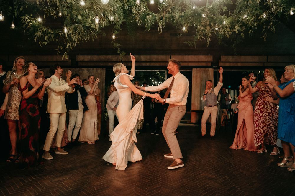 Couple sharing their first dance under twinkling lights at wedding reception.