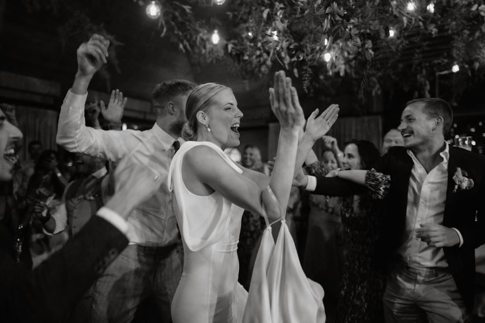 Black and white capture of energetic dancing during wedding reception celebration.