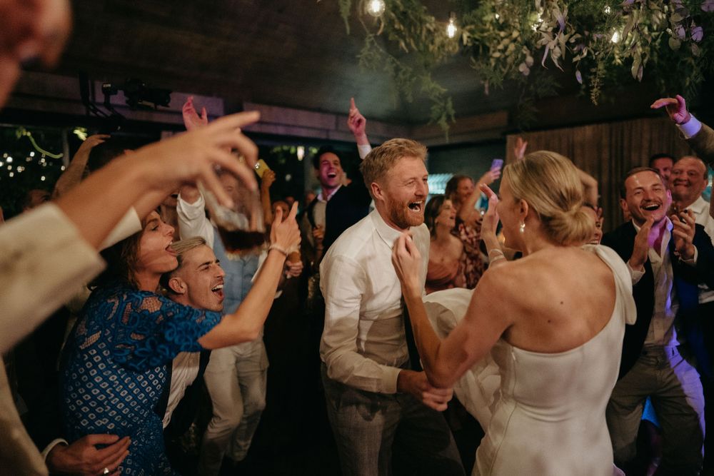 Wedding reception dance floor filled with energetic celebrating guests.